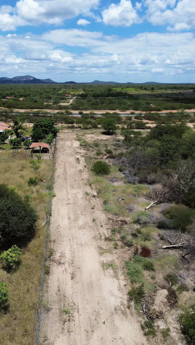Drone: entrada da área com rodovia asfaltada e postes de energia